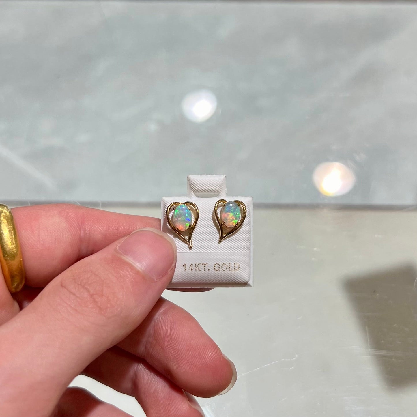 A pair of yellow gold, heart shaped stud earrings set with oval cabochon cut natural opal stones.