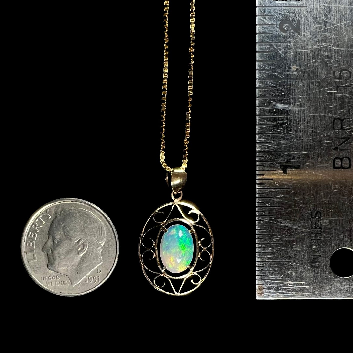 An 18 karat yellow gold filigree opal necklace. The opal has bright green color play.