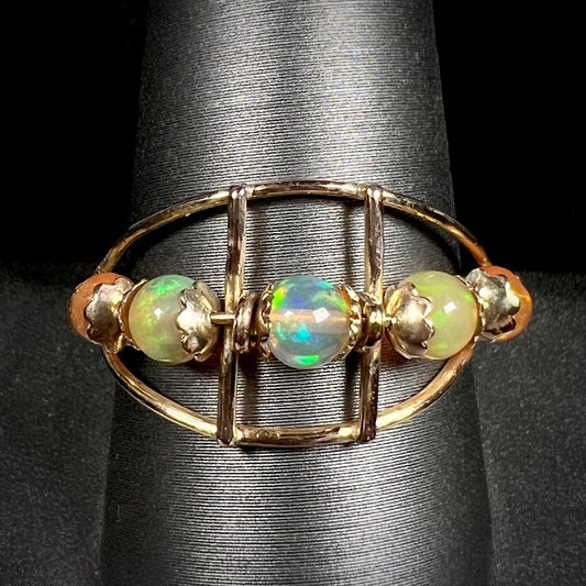 An 18 karat yellow gold ring set with five natural fire opal beads that spin along the ring.