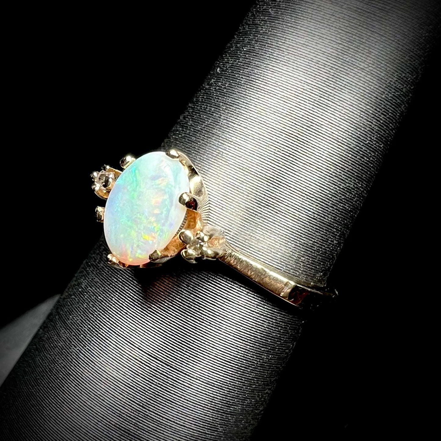 A dainty, 1960's style opal and diamond engagement ring. The ring is prong-set and yellow gold.