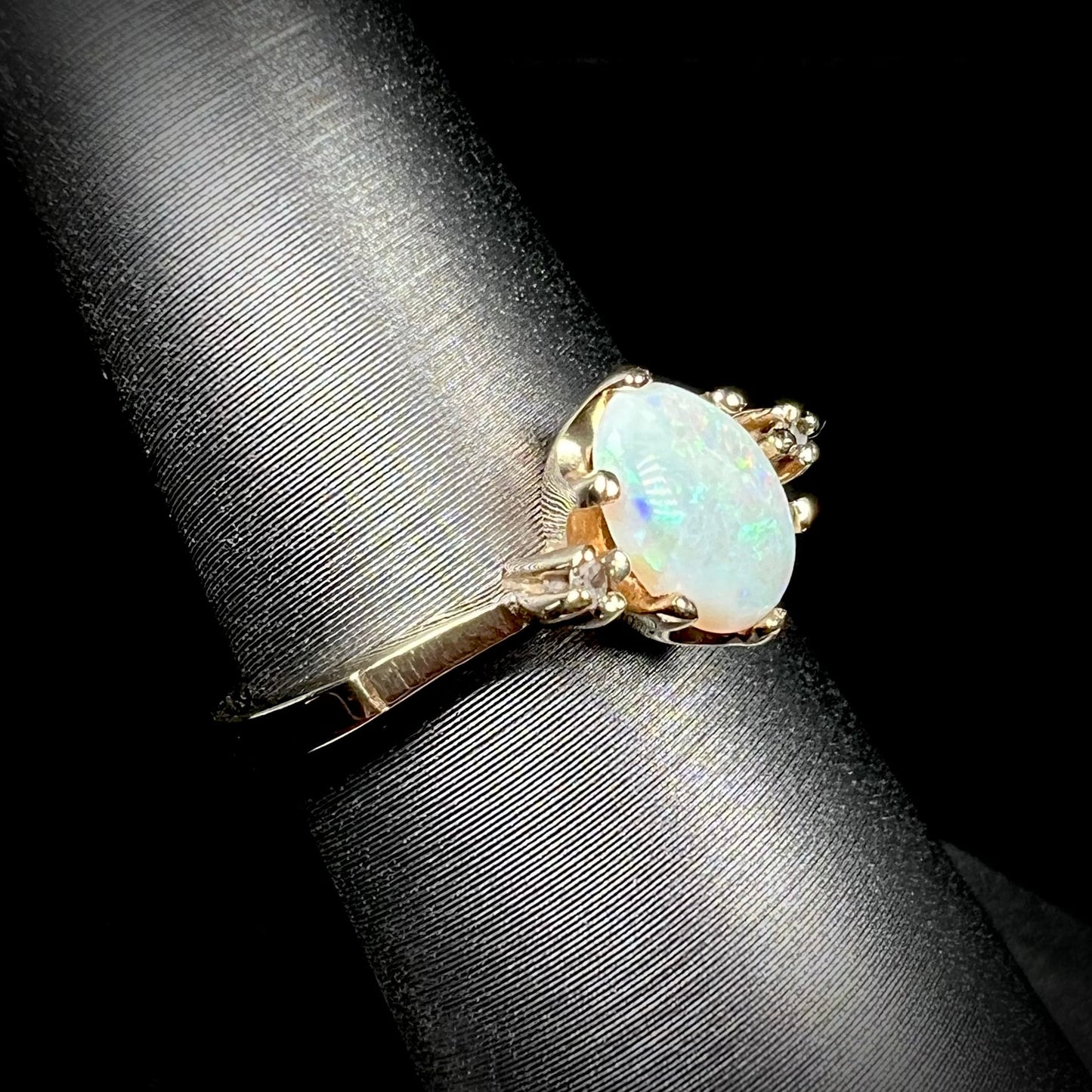 A dainty, 1960's style opal and diamond engagement ring. The ring is prong-set and yellow gold.