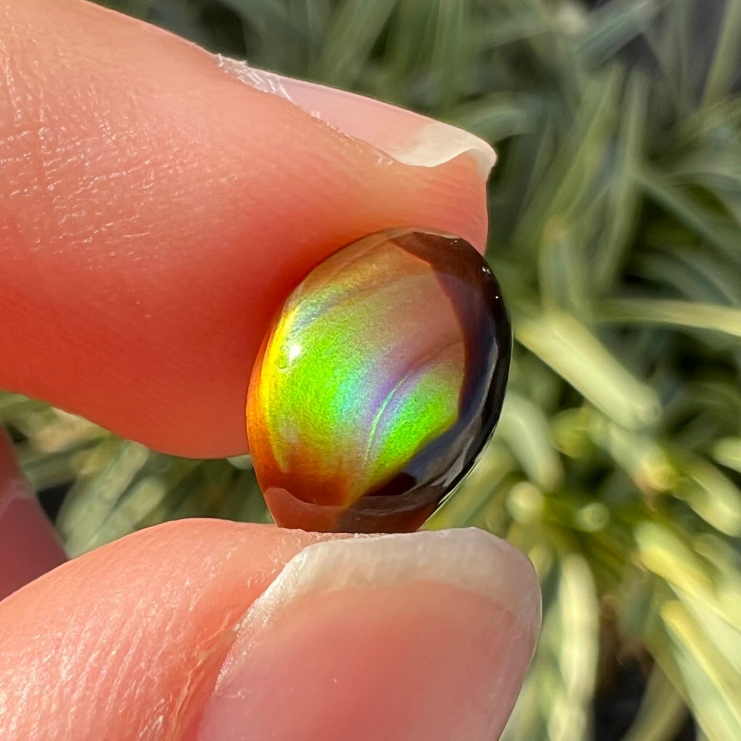 A loose, 3.38ct, pear shaped Mexican fire agate stone. The stone shines a vivid, bright green color with a purple streak.