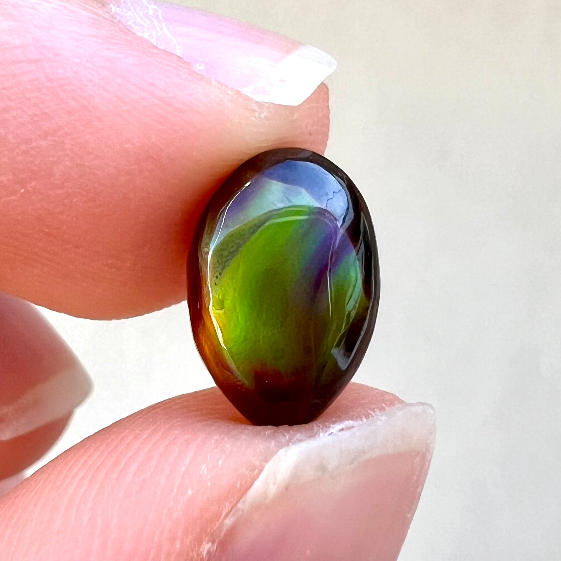 A loose, 3.38ct, pear shaped Mexican fire agate stone.  The stone shines a vivid, bright green color with a purple streak.