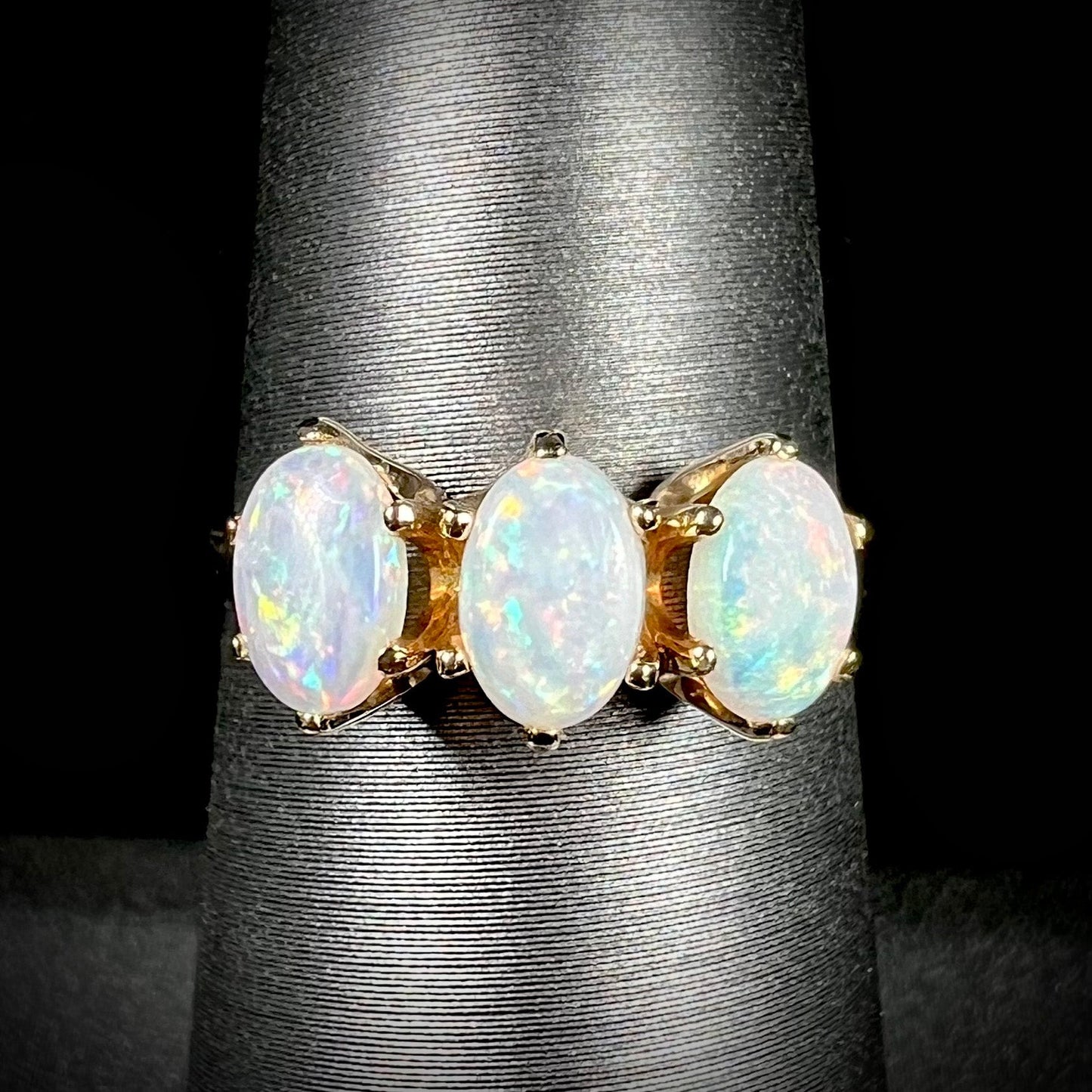 A vintage yellow gold ring mounted with three oval cut white Australian opals.