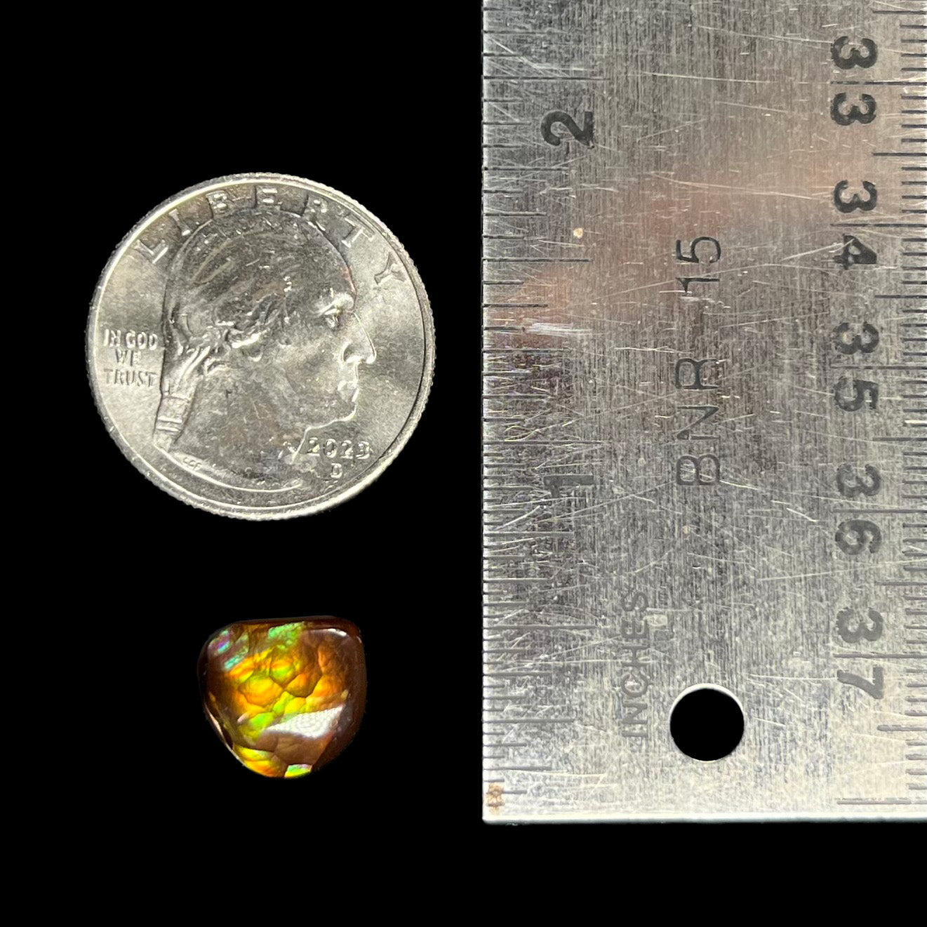 A freeform cabochon cut Mexican fire agate stone.  The stone has a bright purple flash with green, yellow, and orange.