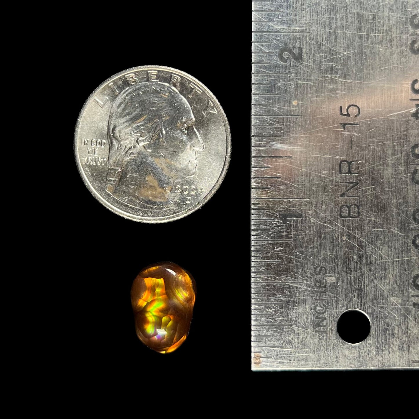 A loose, freefrom cabochon cut Mexican fire agate stone. The stone has red, green, yellow, and purple banding.