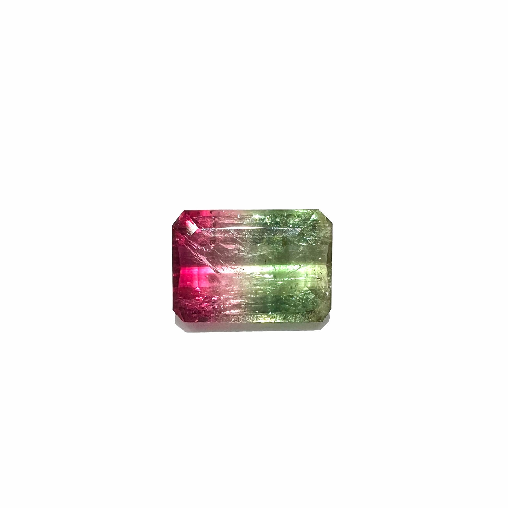 A loose watermelon tourmaline gemstone.  The stone is emerald cut and fades from hot pink to green.