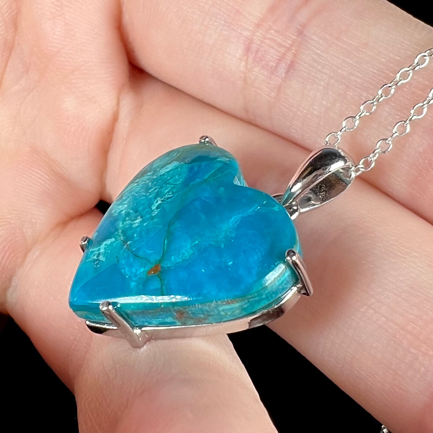 Opposite side view of blue heart opal pendant showing matrix details and silver prongs.
