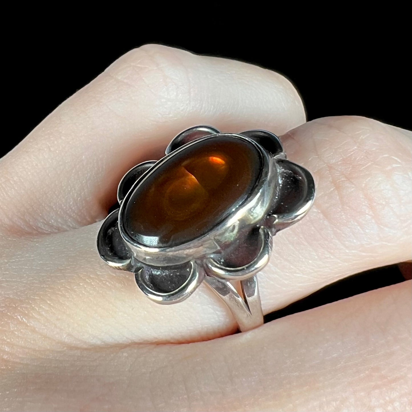 Angled view of fire agate ring on hand, mostly brown with subtle flash.