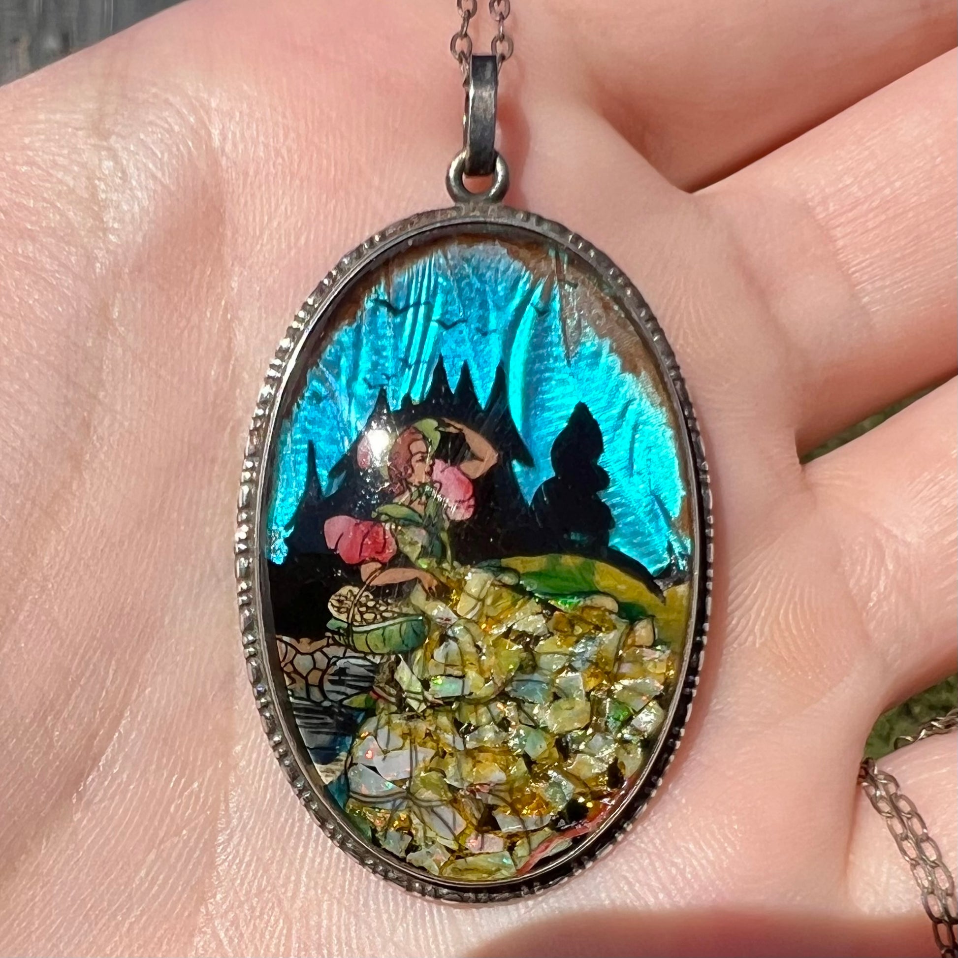 An antique butterfly wing pendant with blue iridescence and crushed opal, shown close-up in sunlight.