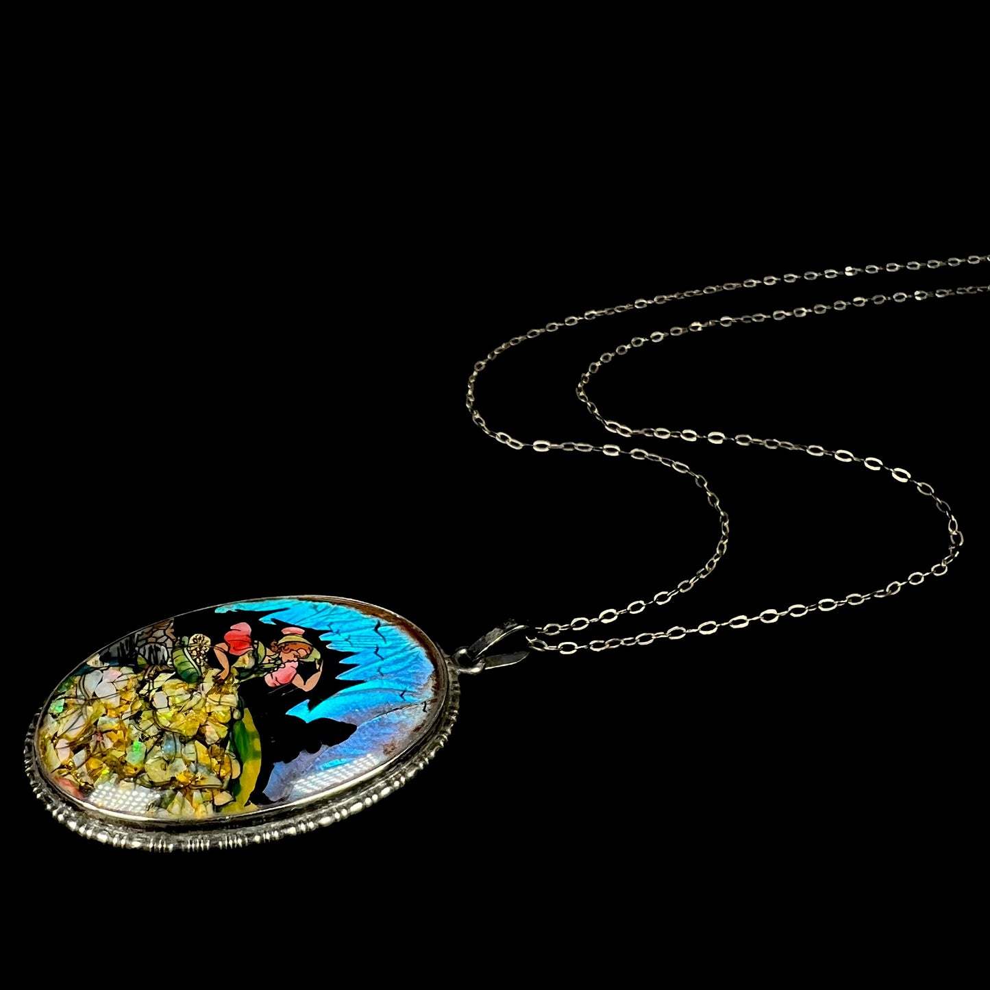 An antique crushed opal and butterfly wing necklace in silver, shown from an angle laying on a black background.