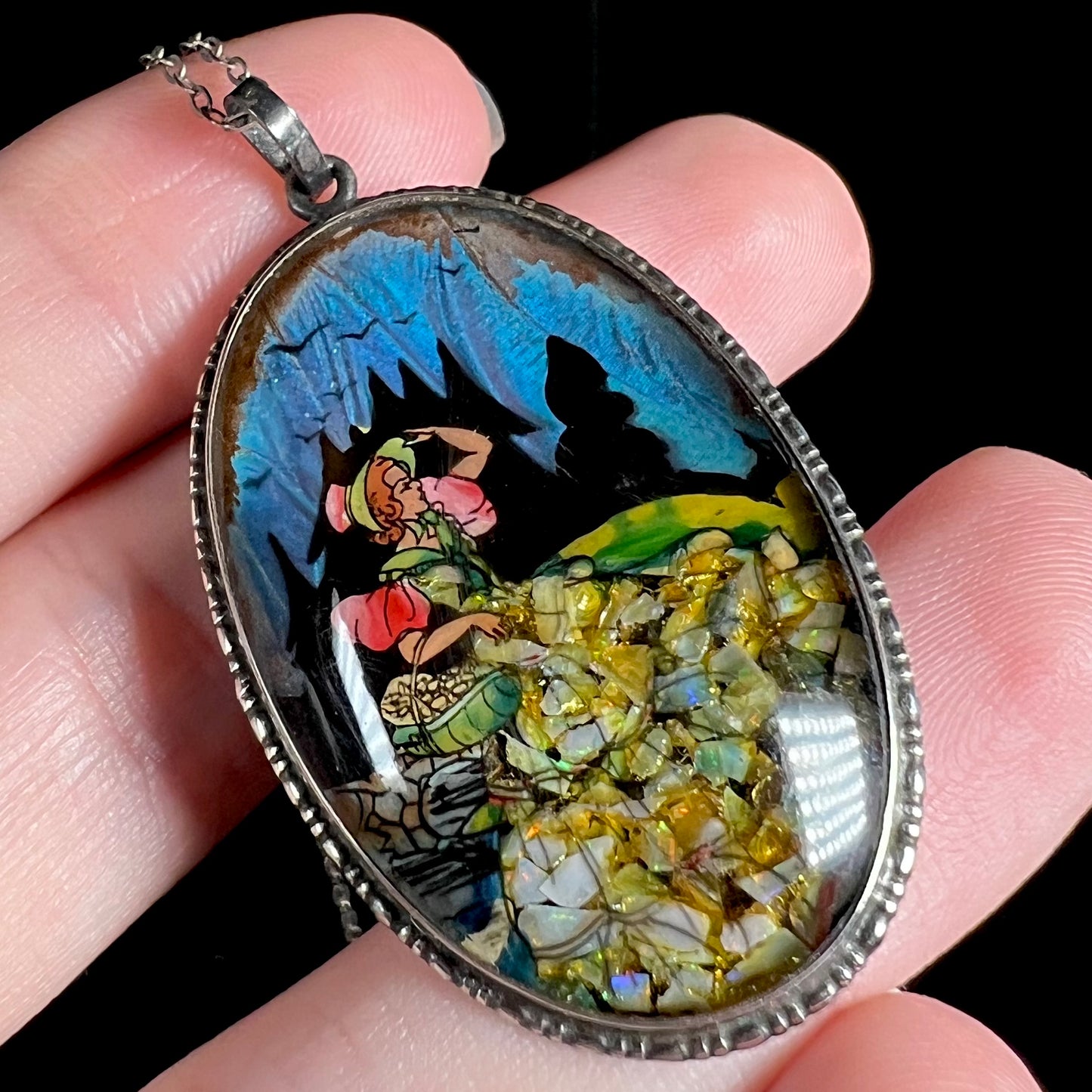 An antique silver English pendant depicting the painted picture of a woman, shown at a close-up angle in a hand.