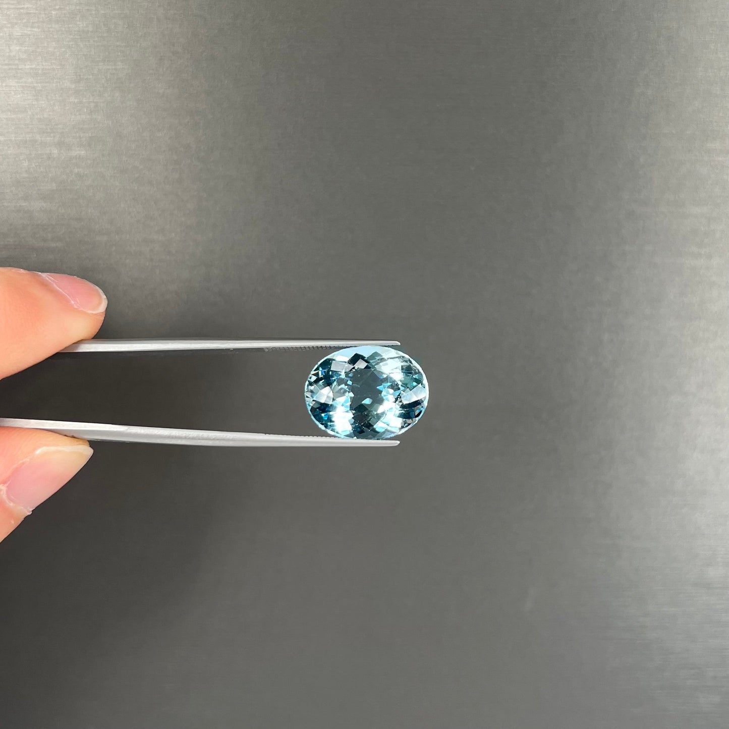 A loose, oval cut Brazilian aquamarine gemstone. The stone is a rich aqua blue color.