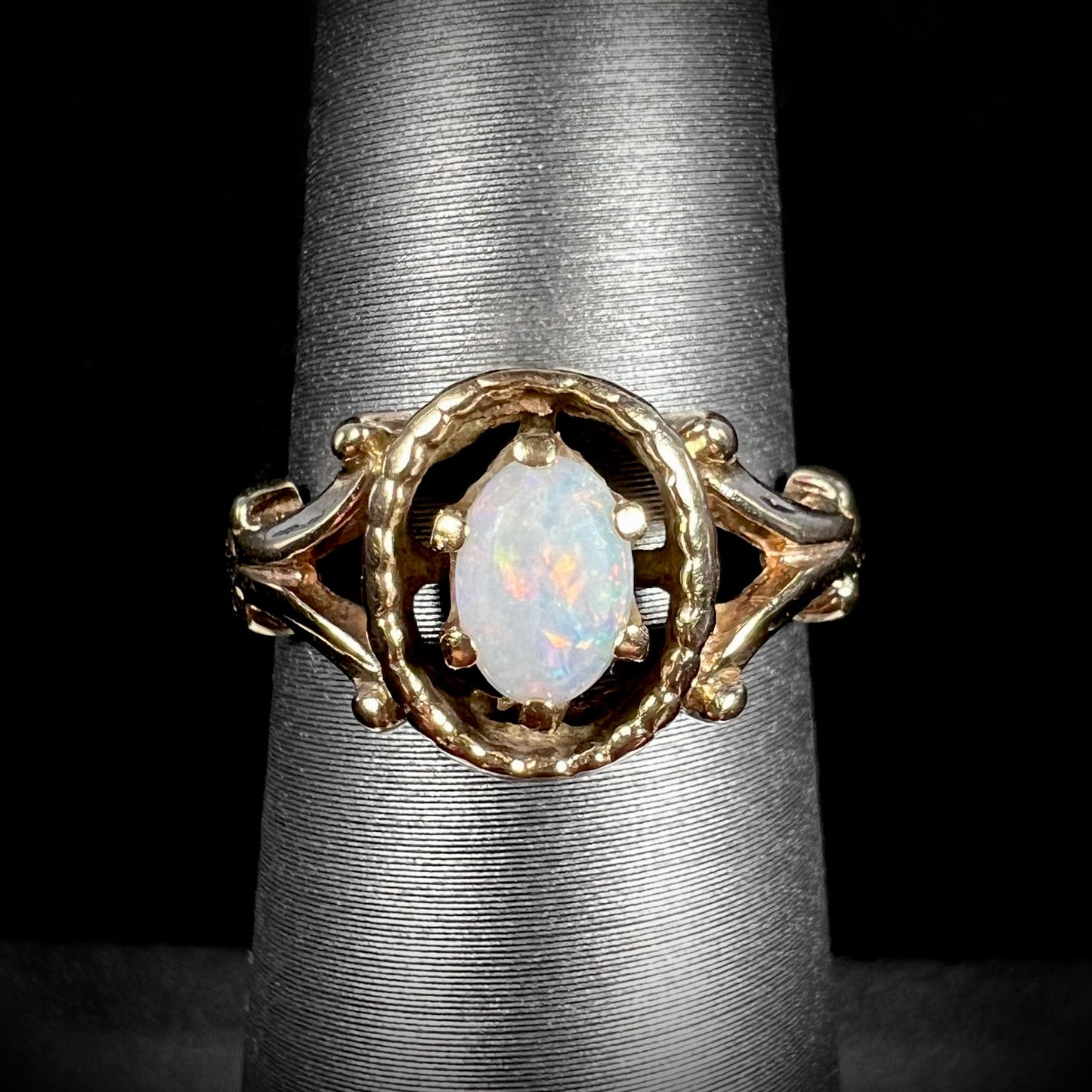 A ladies' Art Nouveau style opal solitaire ring. The mounting is yellow gold with filigree accents.