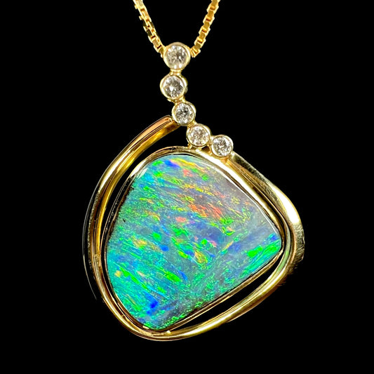 Macro view of a clean face boulder opal pendant with vibrant multicolor fire on a black background