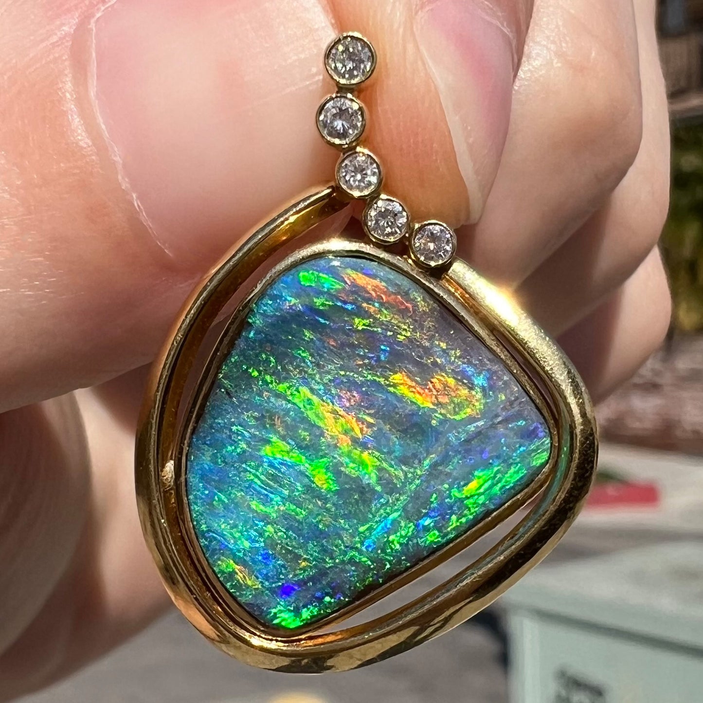Pendant held in sunlight in urban setting with green, orange, and blue fire visible