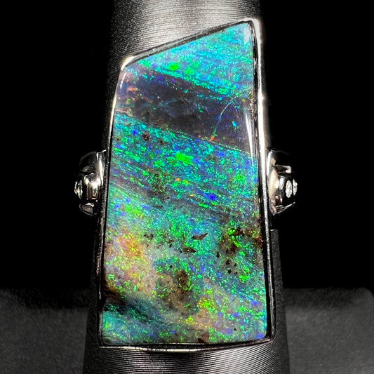 An 11.67ct Australian boulder opal and diamond ring in platinum with green color play, shown on a ring display.