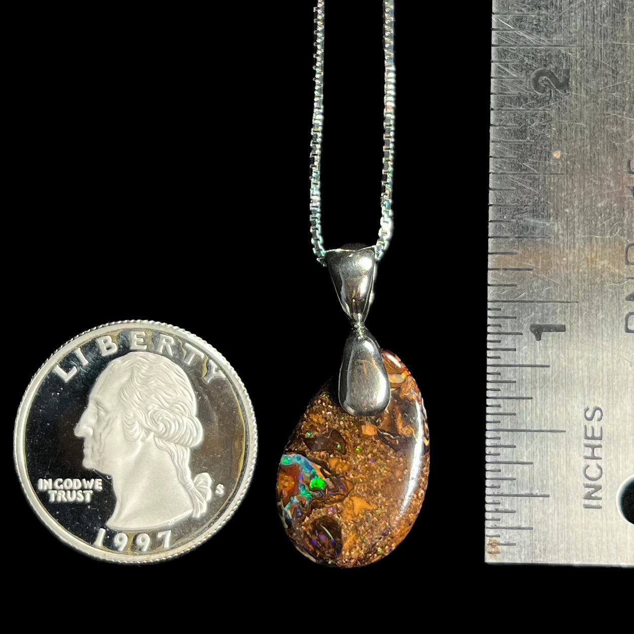 An Australian boulder opal necklace with a sterling silver bail, shown next to a quarter coin and ruler.