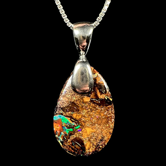 An Australian boulder opal necklace with a sterling silver bail.  The opal has a bright green flash of color.