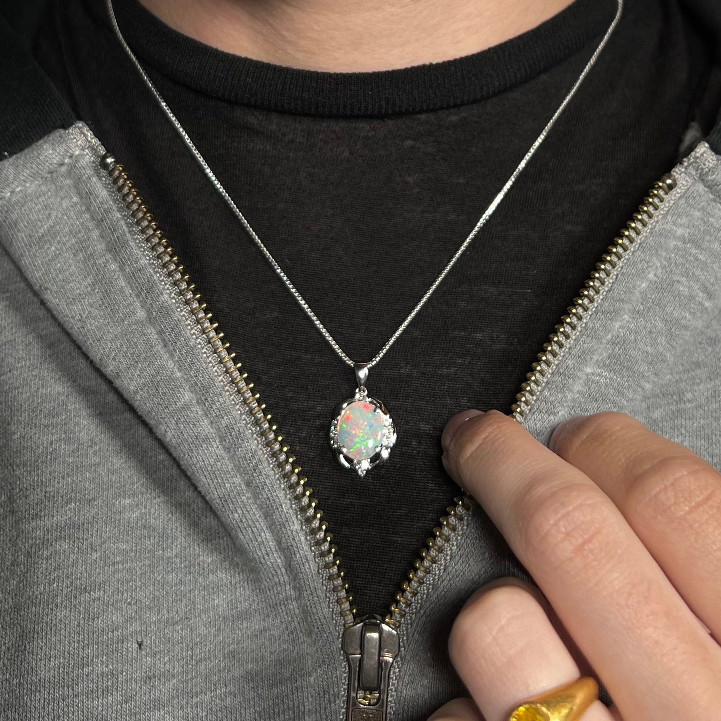 An Australian opal and diamond necklace made from platinum, worn around a neck. The opal has red flashes.