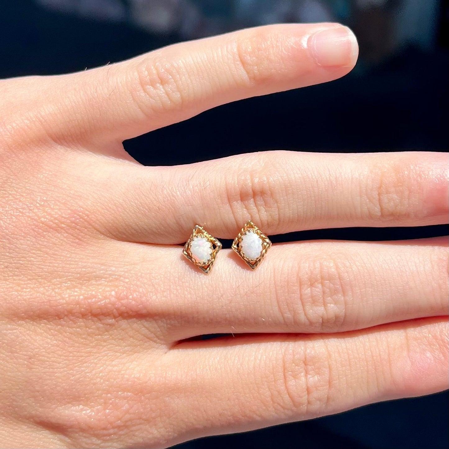 A pair of opal stud earrings. The opals are set in yellow gold diamond shaped mountings.