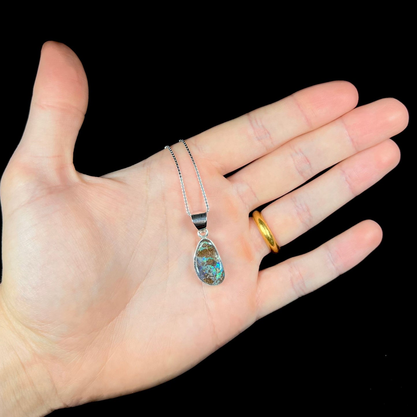 A sterling silver pendant set with an Australian boulder opal on a silver box chain.