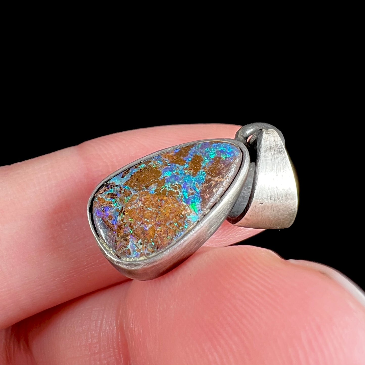 A handmade, satin finish sterling silver pendant set with a drop shaped boulder opal stone.