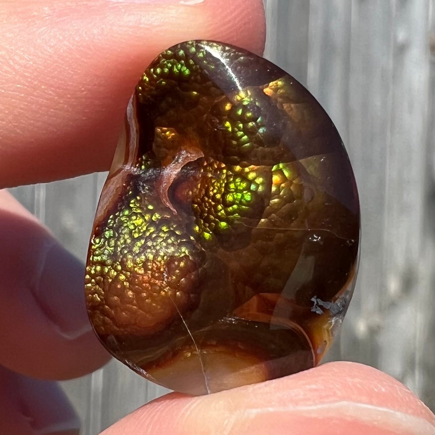 A large Mexican fire agate cabochon. The stone has a bubbly green pattern.