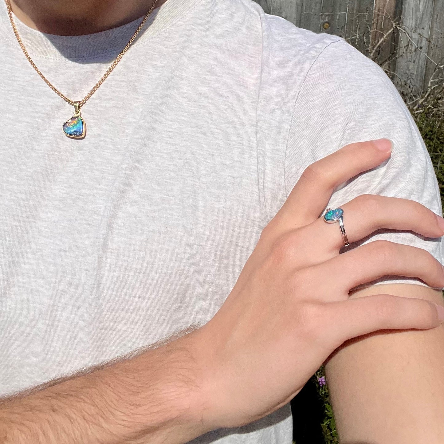 A sterling silver ring bezel-set with an oval shaped black opal doublet. The opal has red and blue fire.