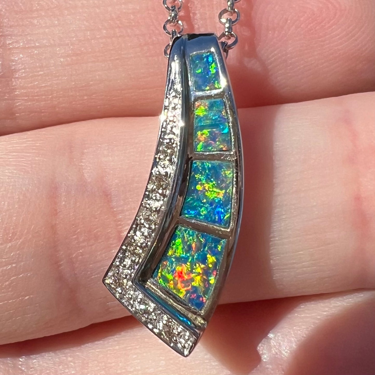 Straight-on macro close-up of the opal in sunlight, revealing vibrant multicolor fire with flashes of red, green, orange, and blue.