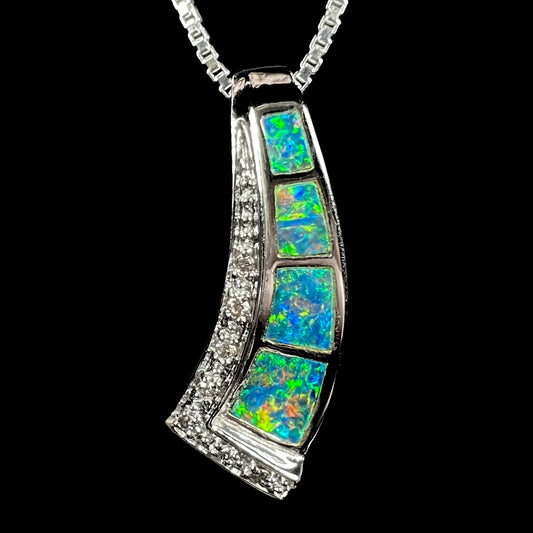 A wave-form black opal inlay pendant in 18k white gold, showcasing green undertones with subtle color play.