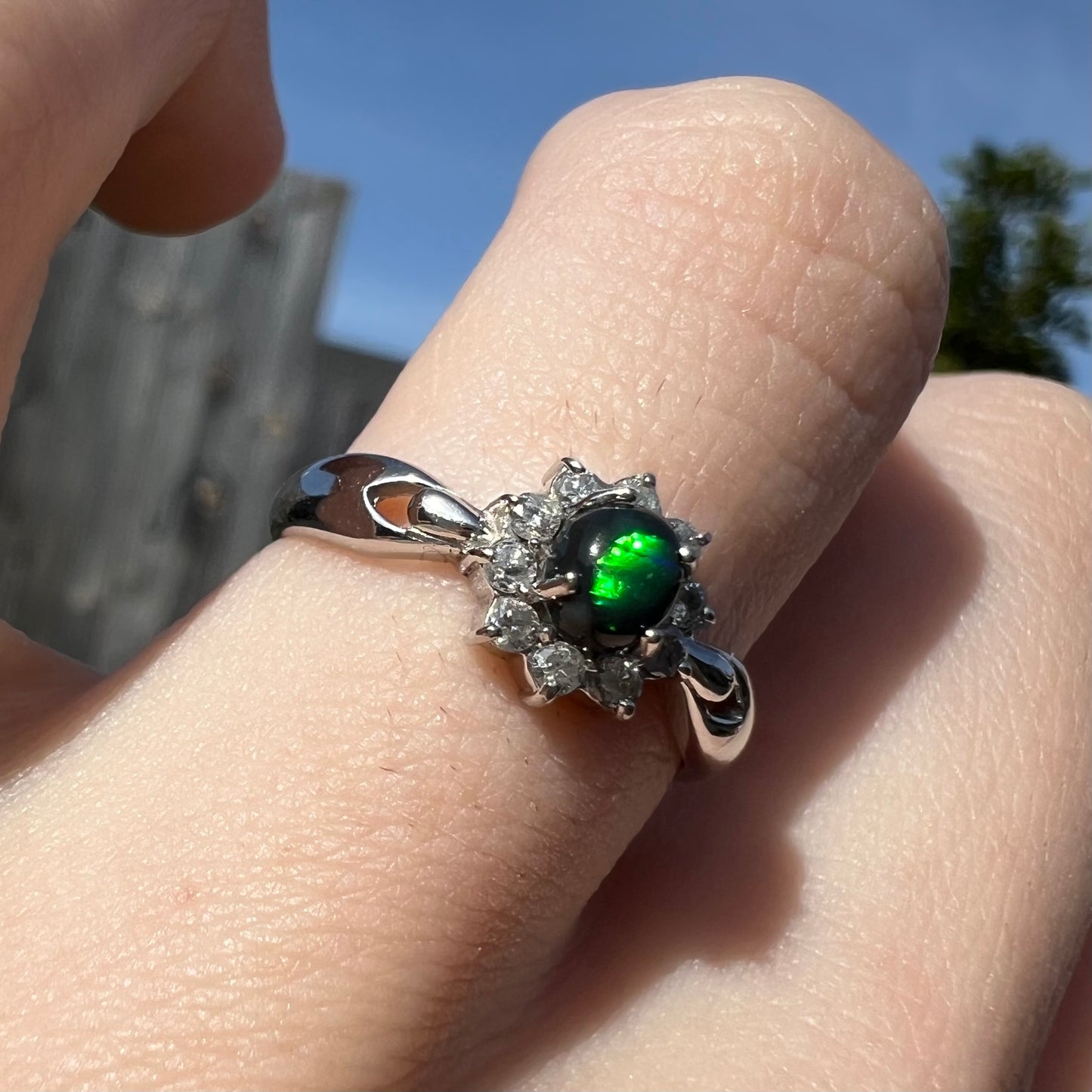 Macro angled view of opal ring showing brightest green color play in sunlight.