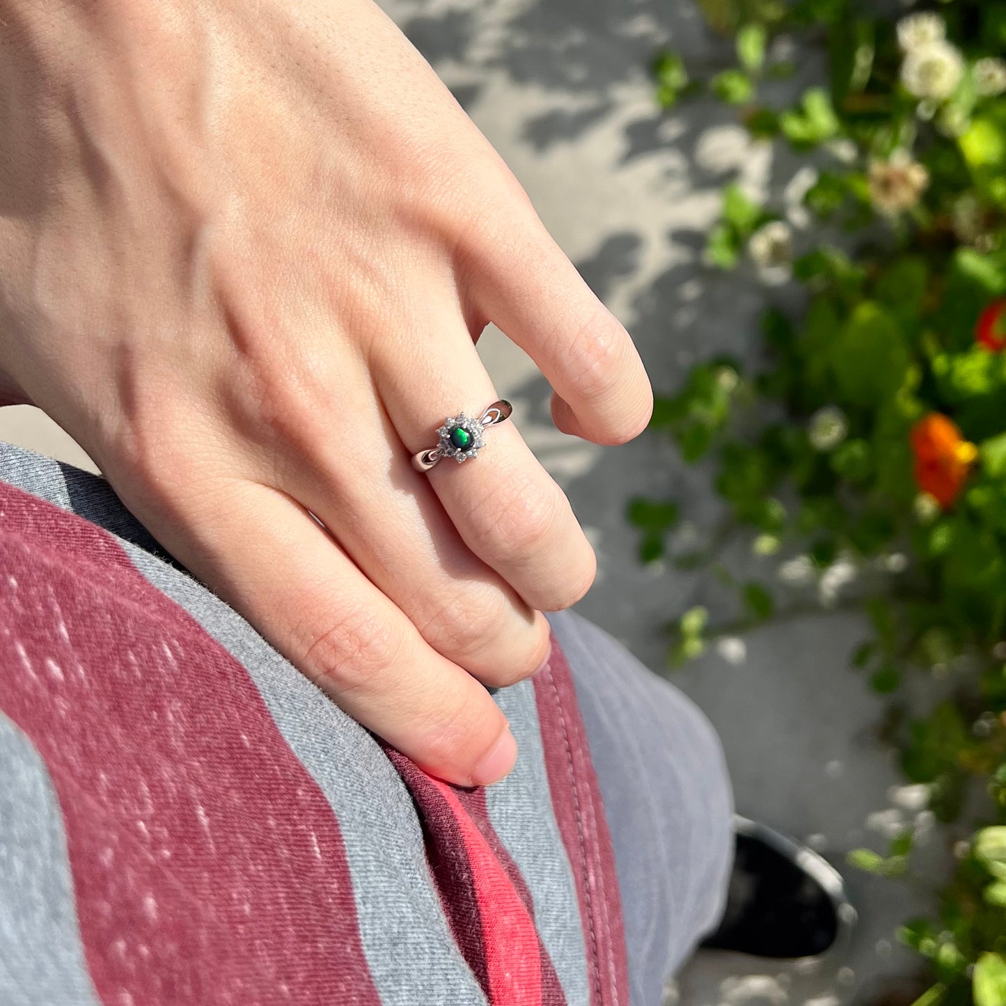 Lifestyle photo of opal ring on hand at hip with bright green flash visible in the opal.