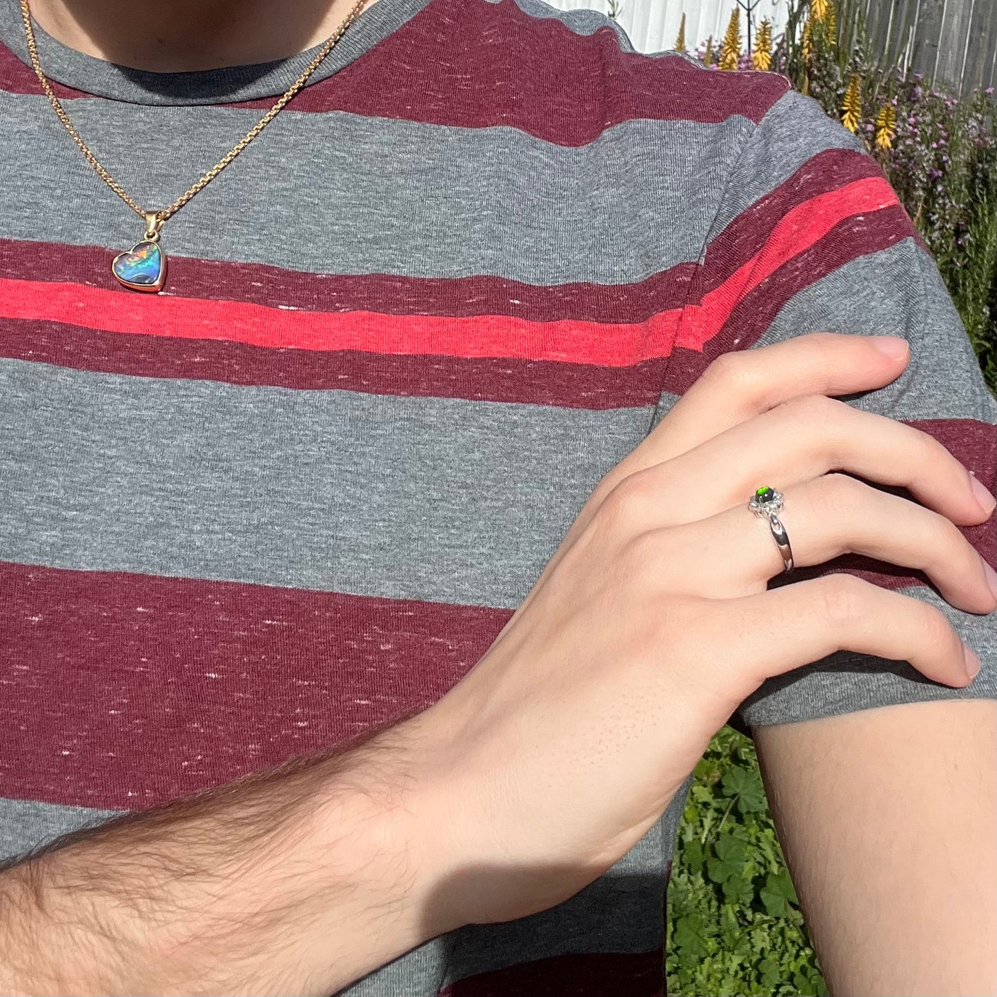 Lifestyle photo of opal ring on hand resting on shoulder with striped shirt partially visible.