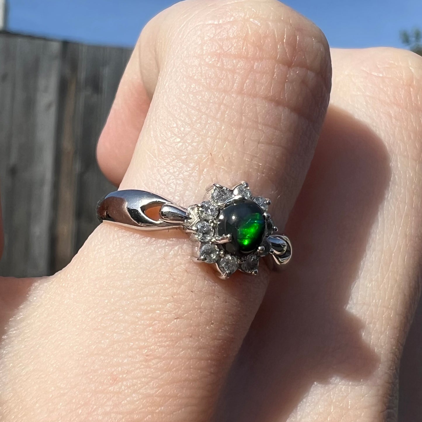 Opposite side outdoor view of ring showing green flash in black opal center.
