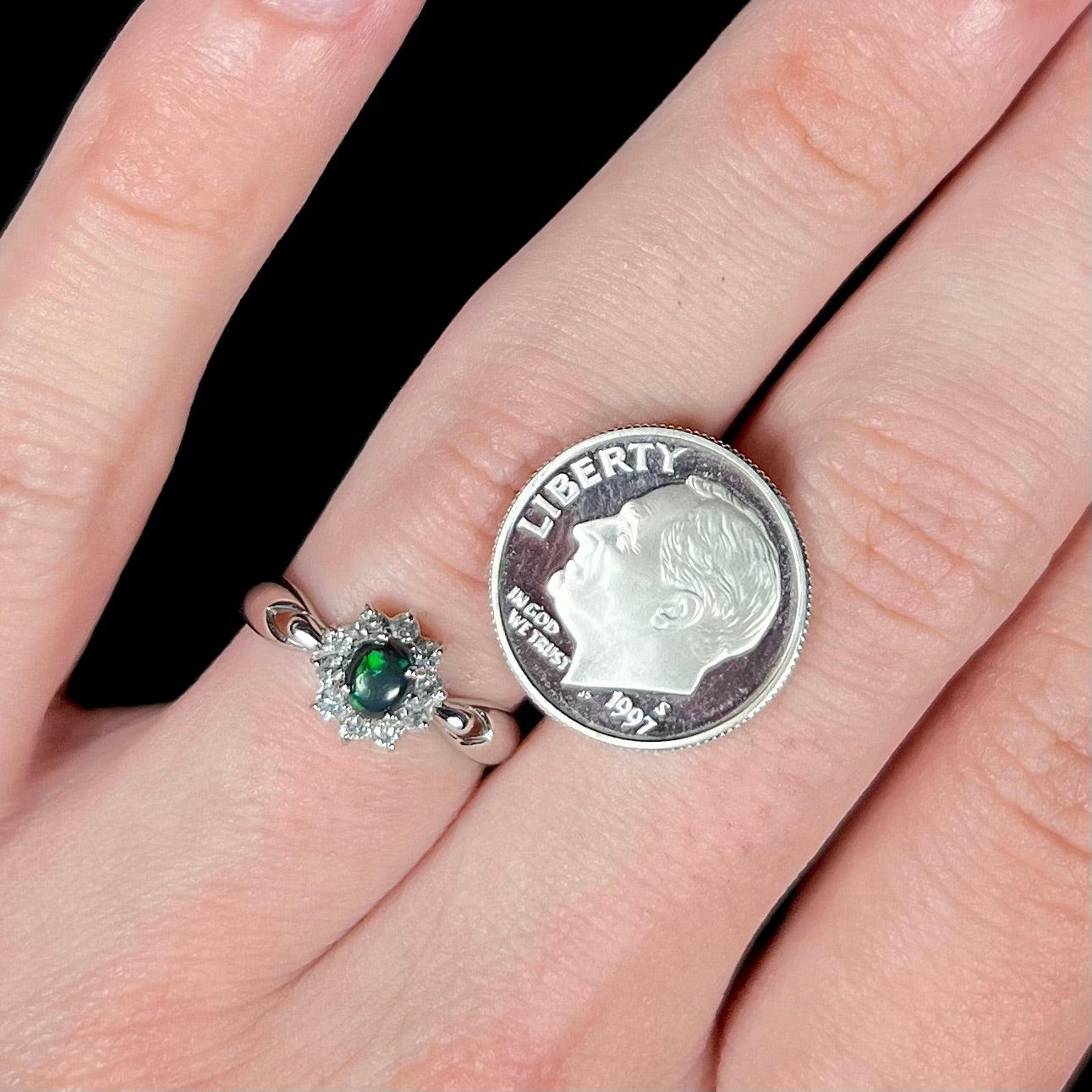 Macro shot of opal ring with dime for scale, green flashes visible in the stone.