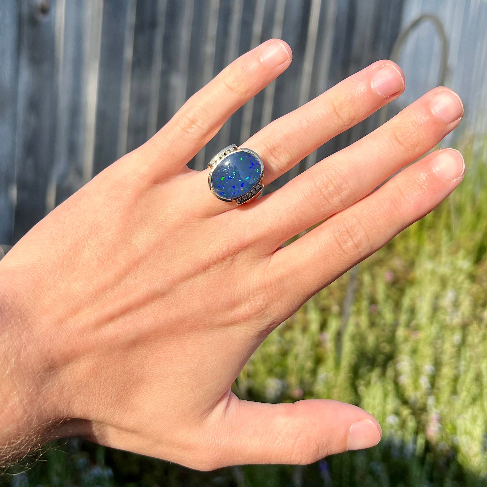 A large, unisex gold ring mounted with a half-bezel set black opal doublet and diamonds.
