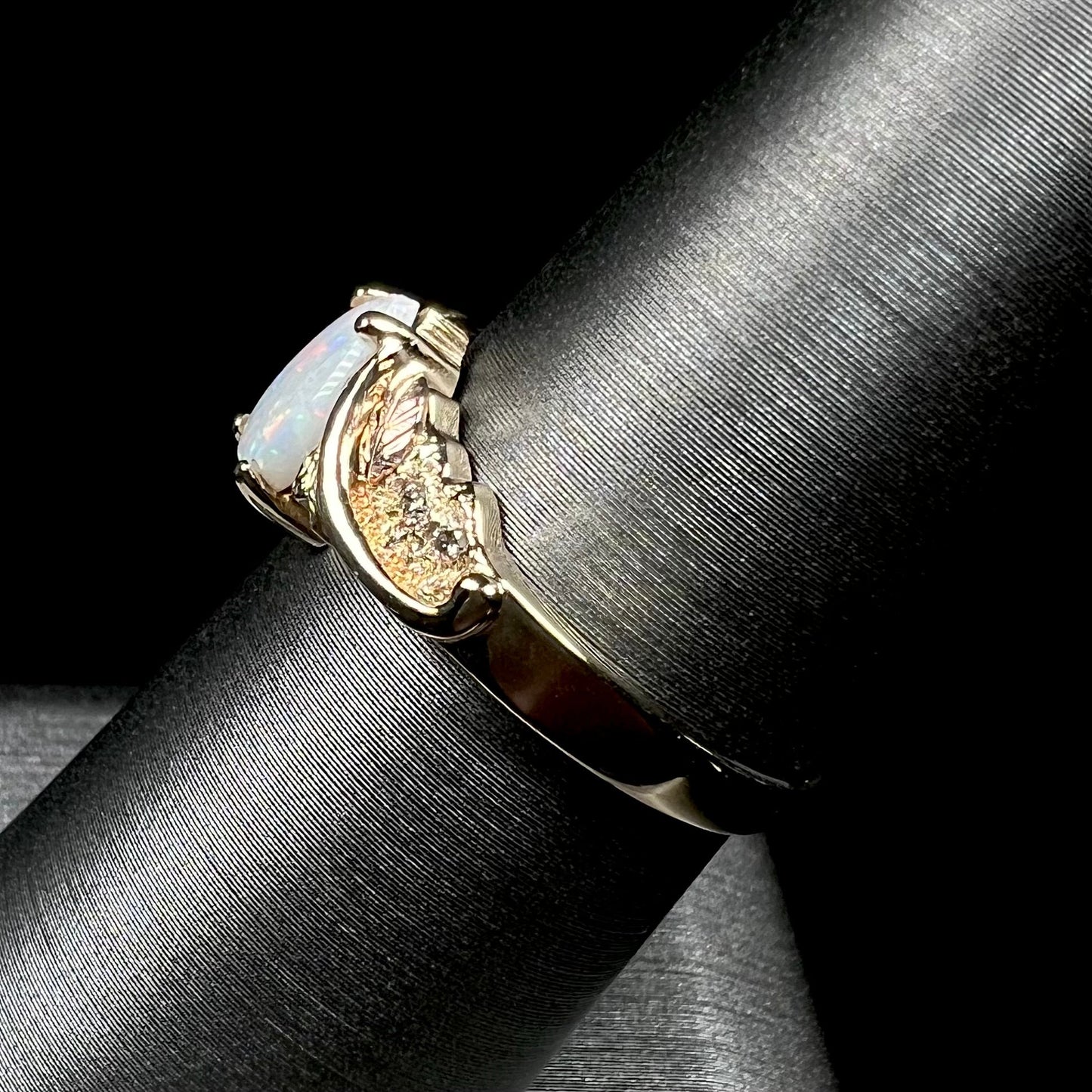 A ladies' two-tone yellow and rose Black Hills gold opal and diamond ring. The opal is a pear shaped cabochon.