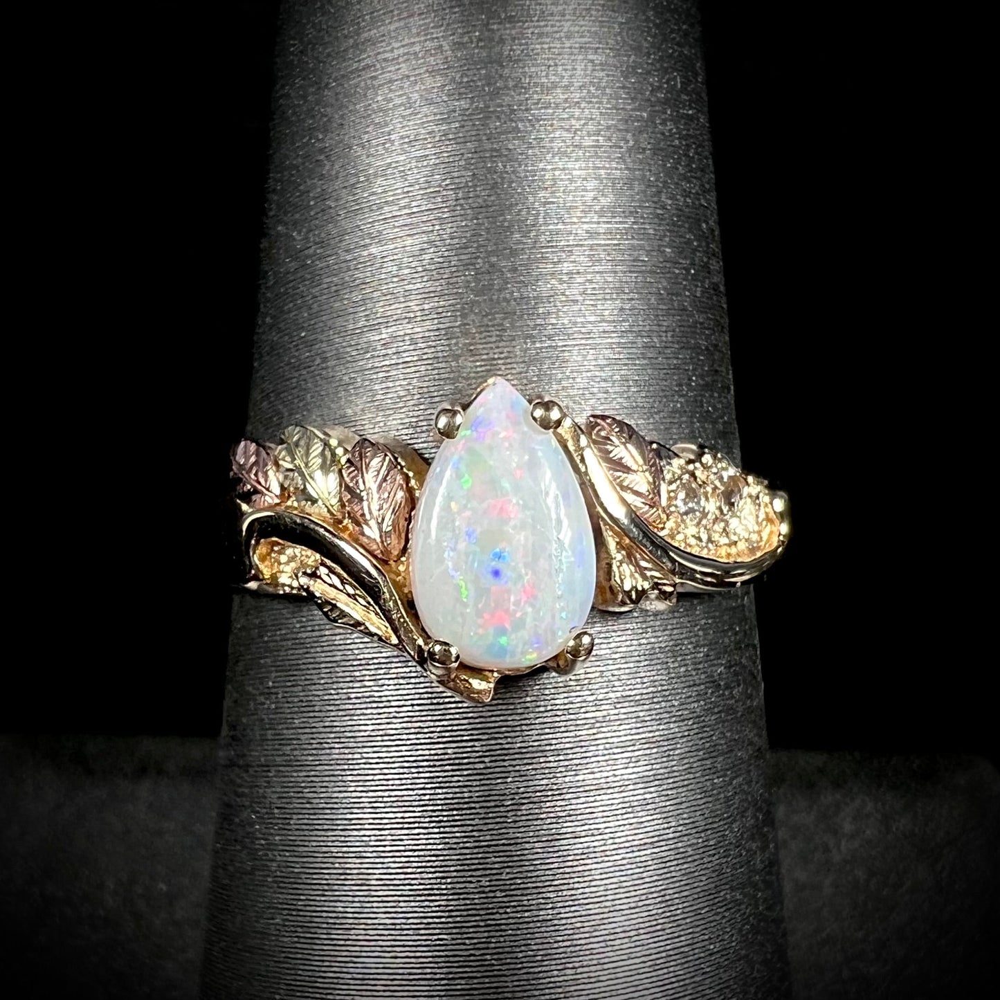 A ladies' two-tone yellow and rose Black Hills gold opal and diamond ring. The opal is a pear shaped cabochon.
