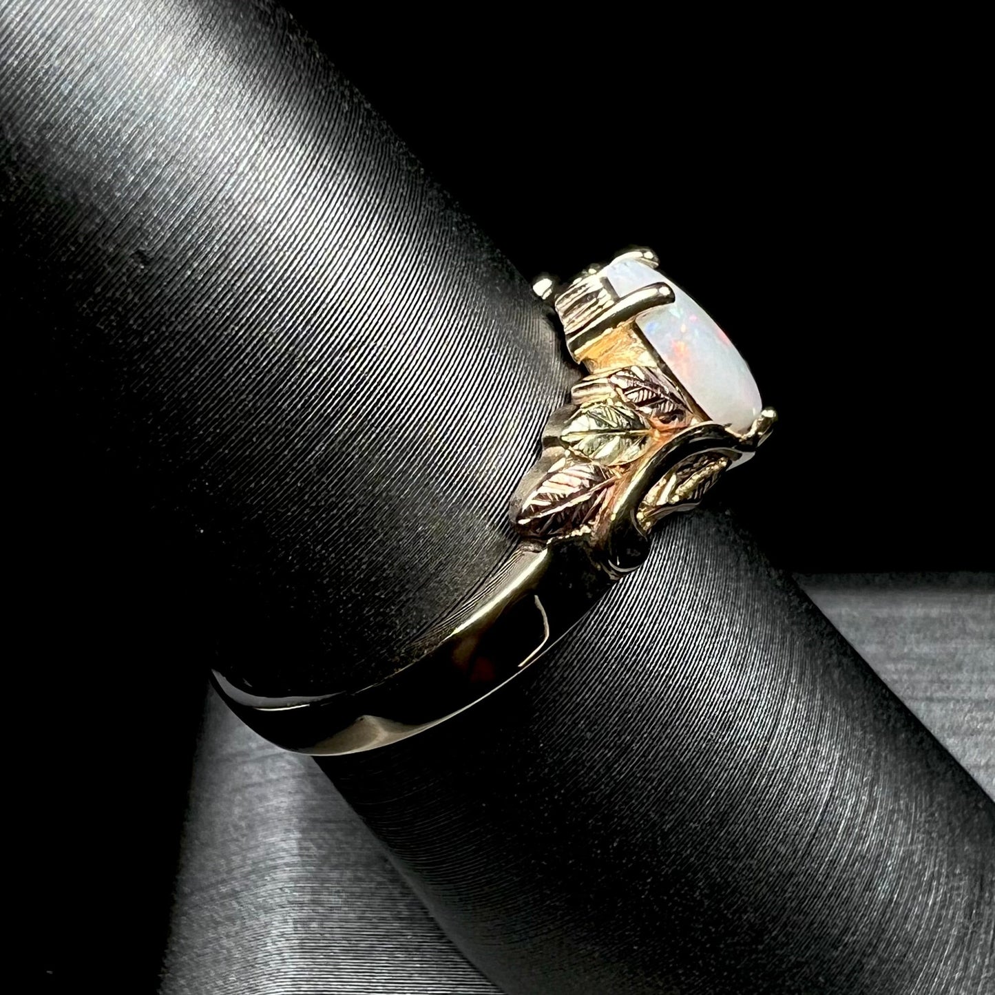 A ladies' two-tone yellow and rose Black Hills gold opal and diamond ring. The opal is a pear shaped cabochon.