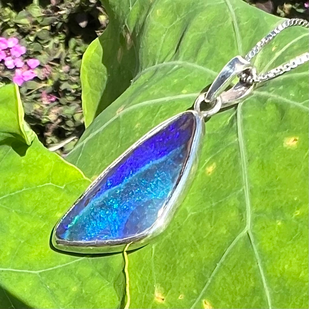 A sterling silver necklace set with a triangle shaped natural black boulder opal.