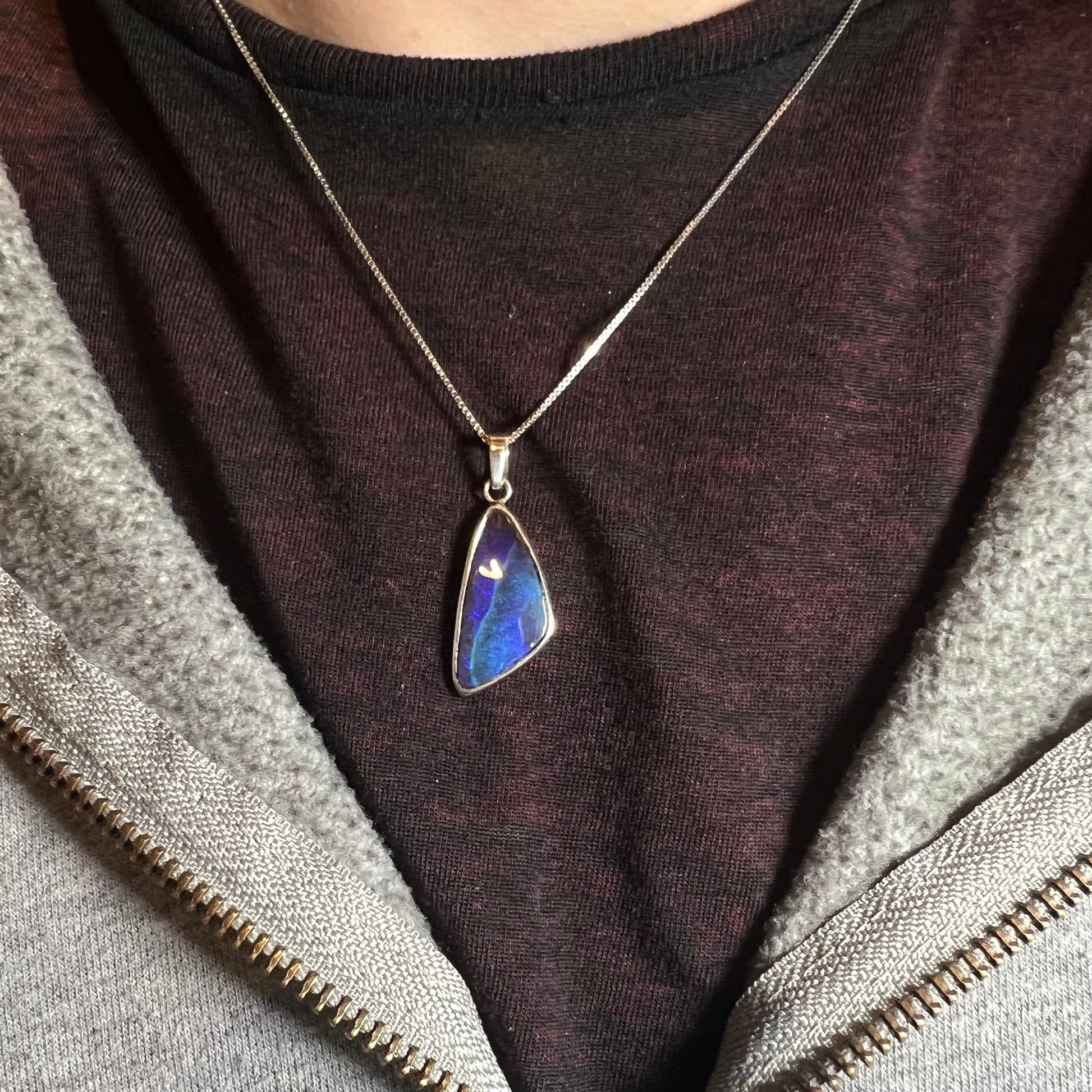 A ladies' sterling silver necklace bezel set with a triangle drop shaped Australian black boulder opal.