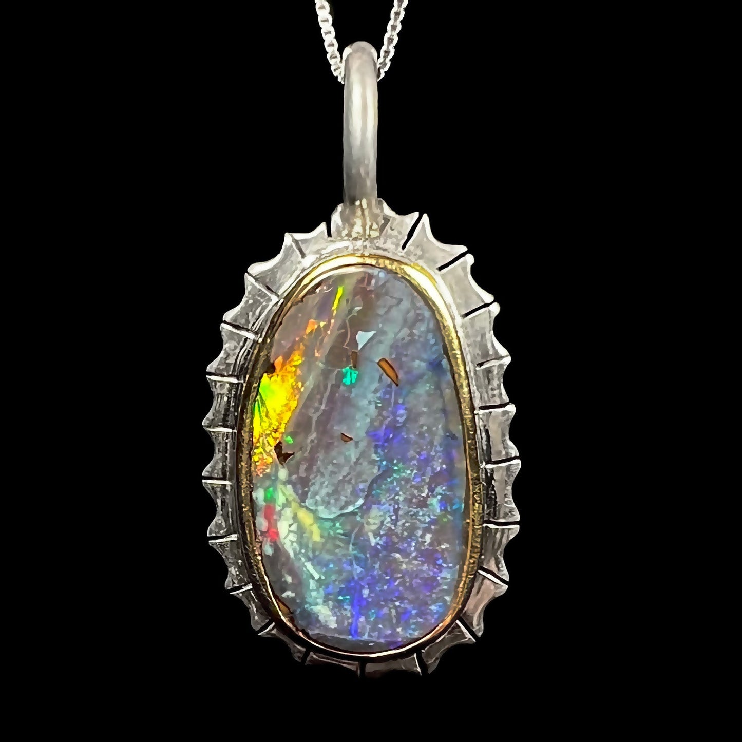 A Southwest style two-tone sterling silver pendant set with a black boulder opal with a yellow gold bezel.