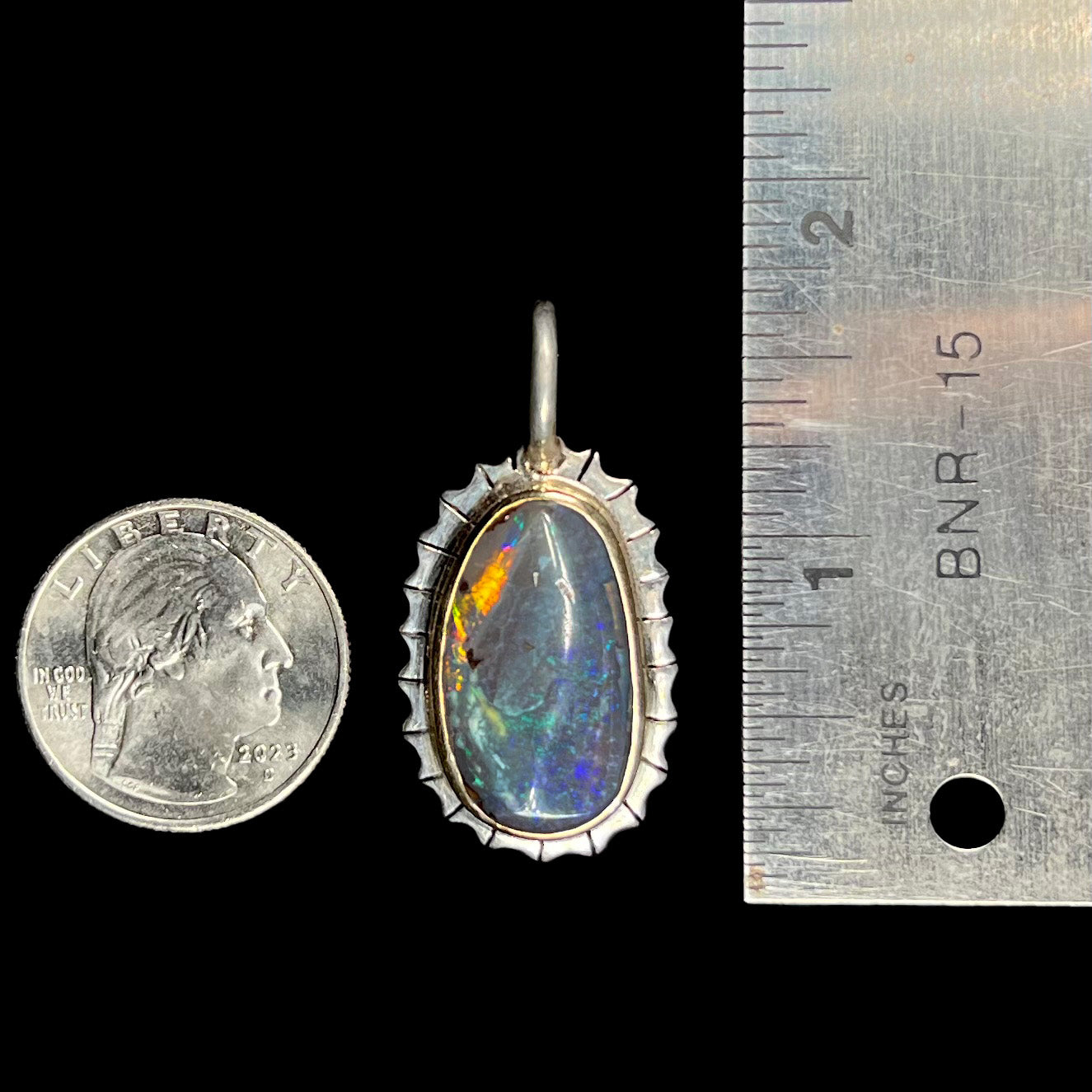 A Southwest style two-tone sterling silver pendant set with a black boulder opal with a yellow gold bezel.