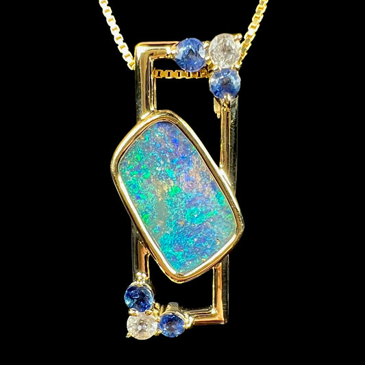 A blue boulder opal pendant set in 18k gold, featuring natural blue and white sapphires.