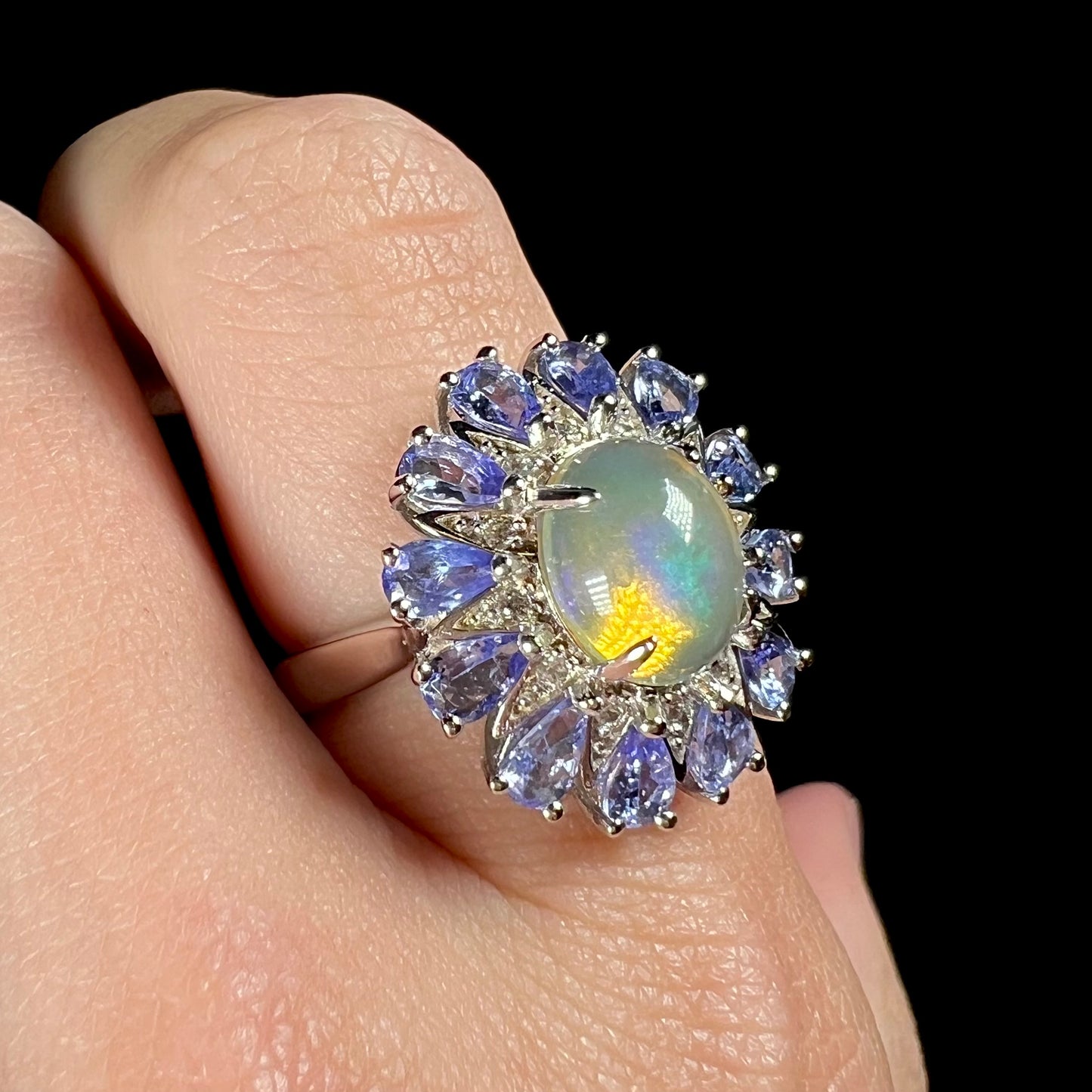A blue Ethiopian opal and tanzanite ring, worn on a finger at an angle.