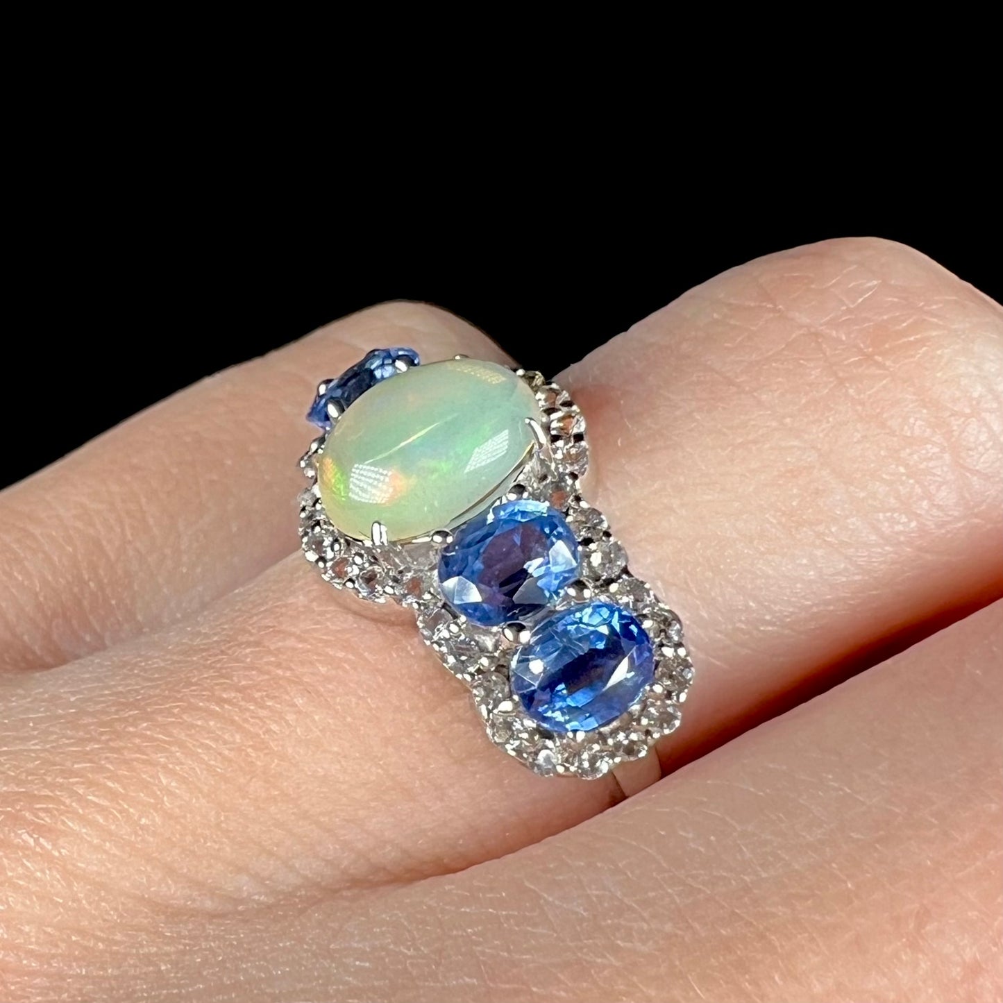 Close-up of a sterling silver Ethiopian opal and kyanite ring worn on a hand.
