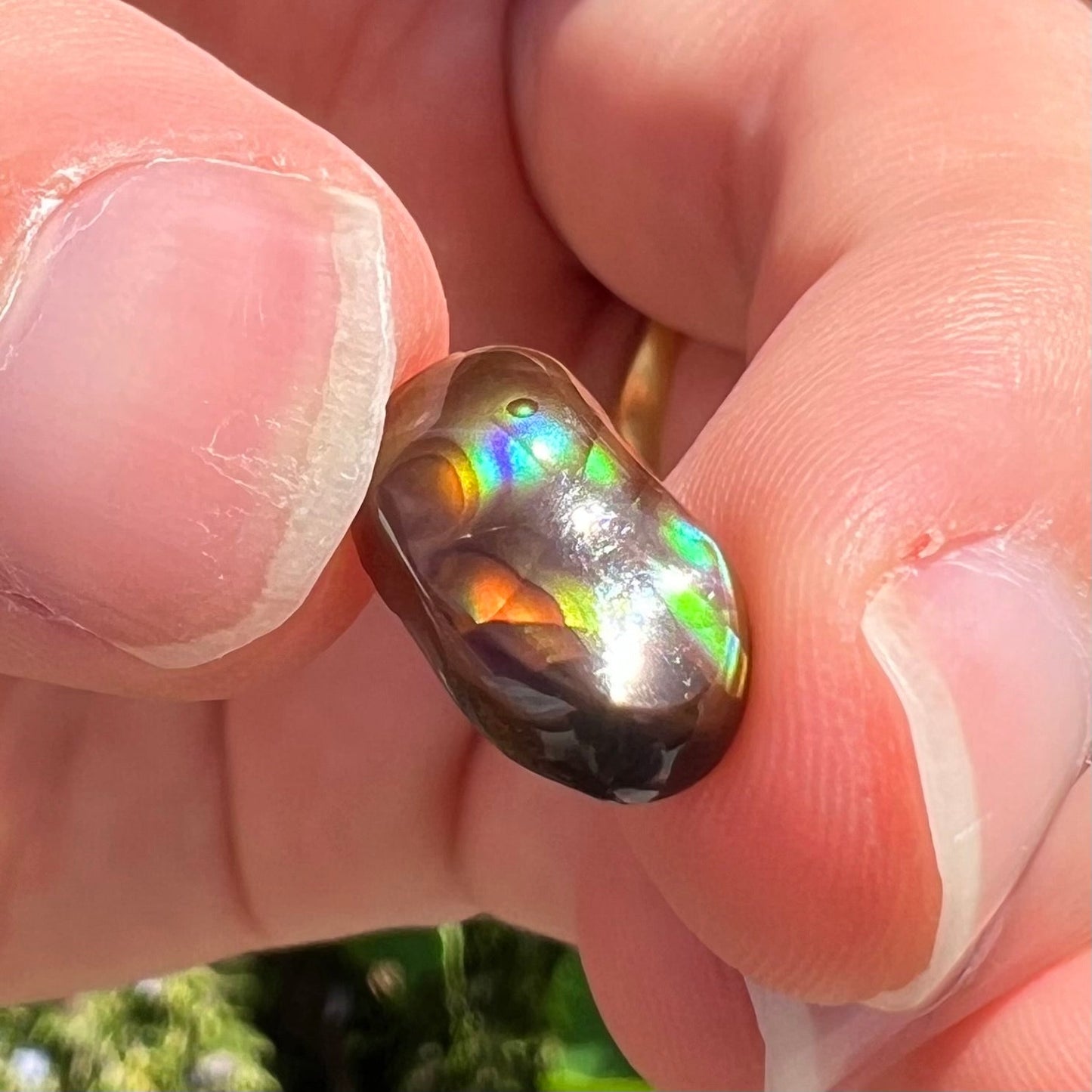 A loose, oval cabochon cut Mexican fire agate stone. The stone has multi-colored banding with blue overtones.