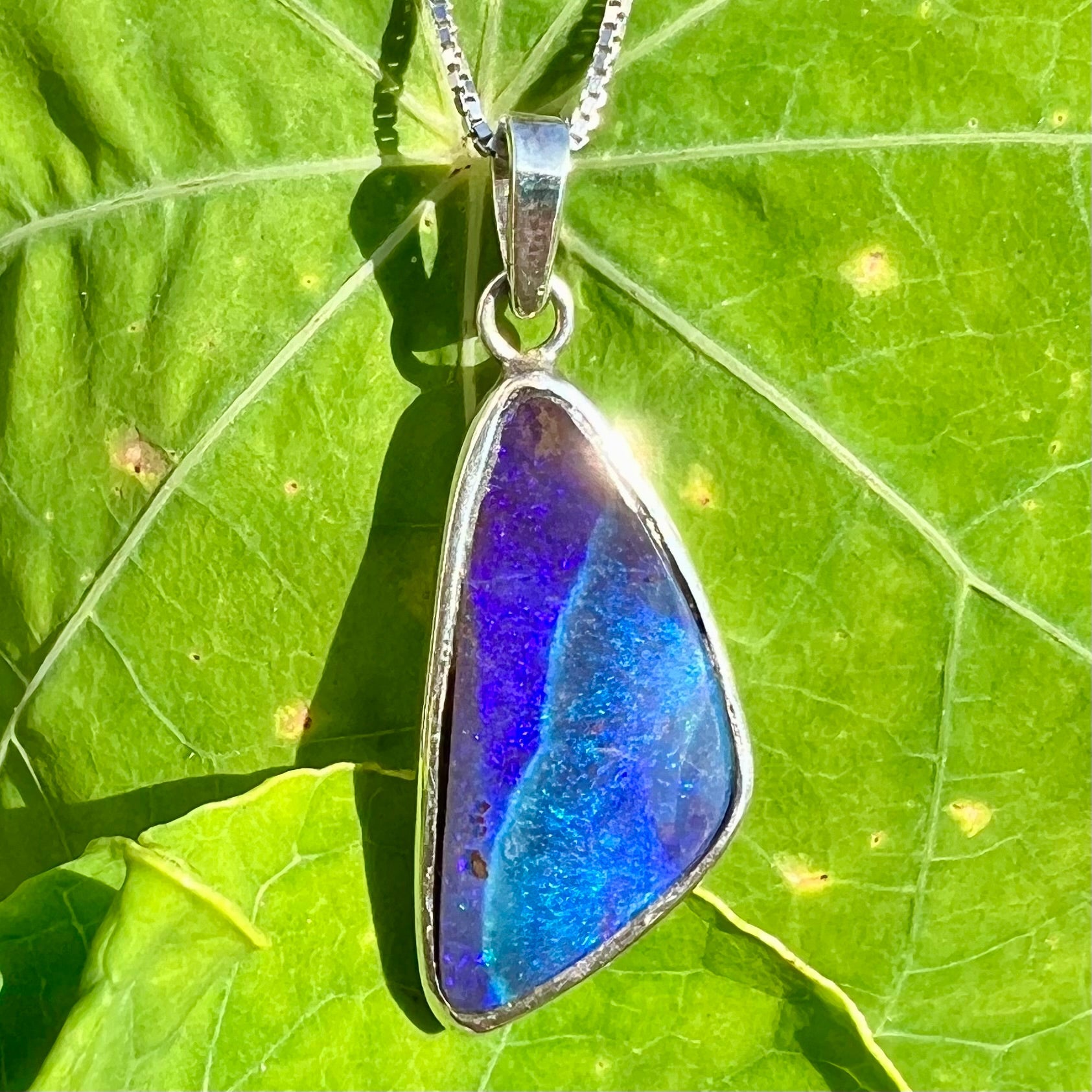 A sterling silver necklace set with a triangle shaped natural black boulder opal.