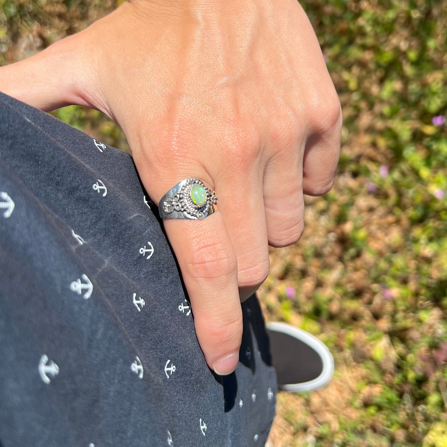 A silver Boho opal men's ring worn on a hand; the hand is resting on the model's hip.